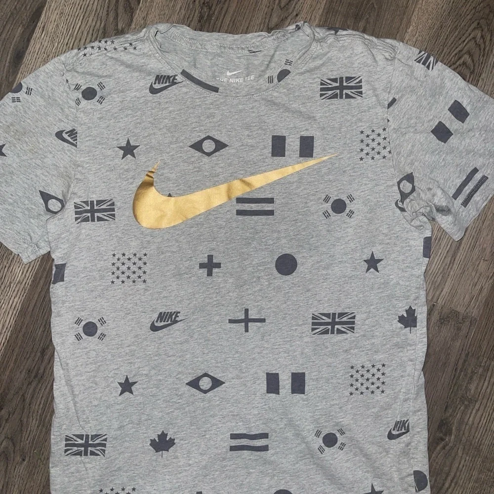 Nike Men's Gray Tee with Gold Swoosh and Flag Patterns